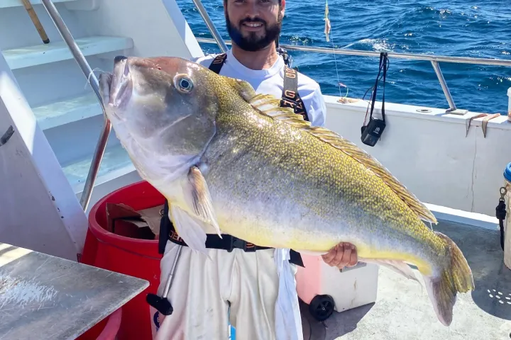 a man holding a fish on a boat in the water