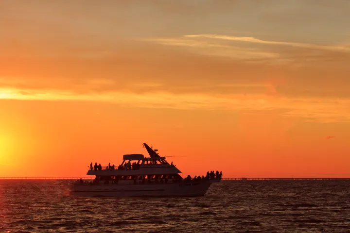 a large ship in a body of water with a sunset in the background