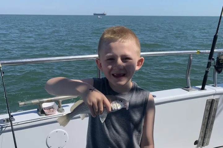 a little boy standing in front of a body of water